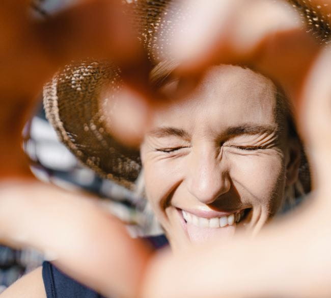 Femme souriant en faisant un cœur avec ses mains