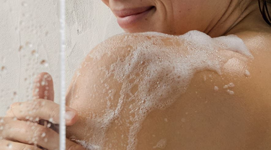 Blonde vrouw met mooie benen naast douche