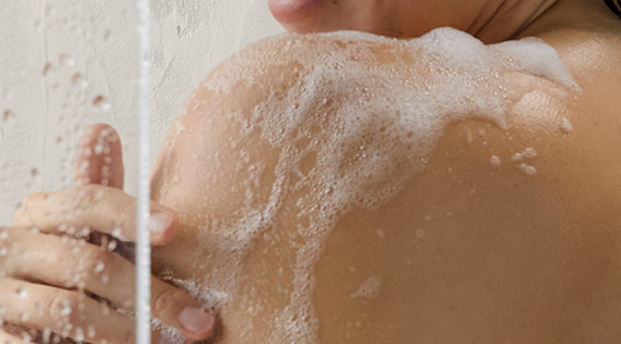 A woman bathing herself with NIVEA in-shower lotion