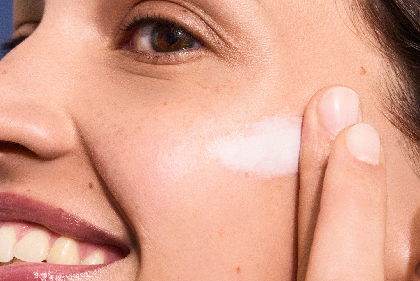 Woman applying cream to her face, highlighting skincare for photoaging