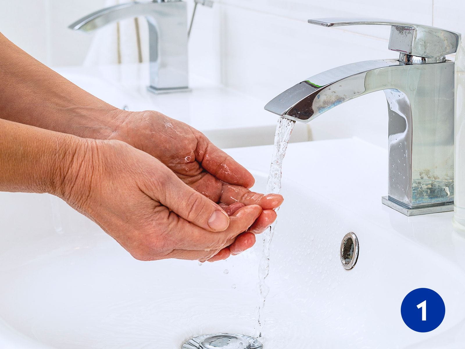 A person washing their hands with water in a sink.