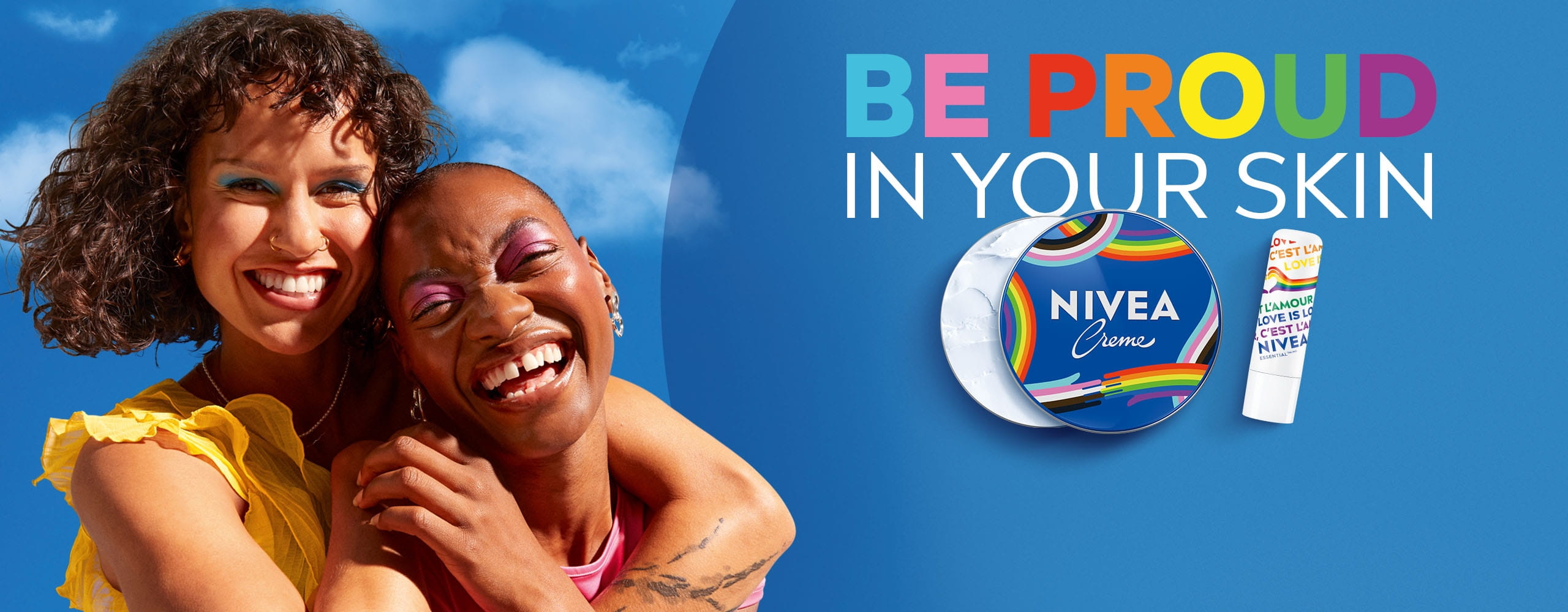 A view of a person looking up, smiling, while holding a NIVEA Creme Tin Pride limited edition product over their right eye.