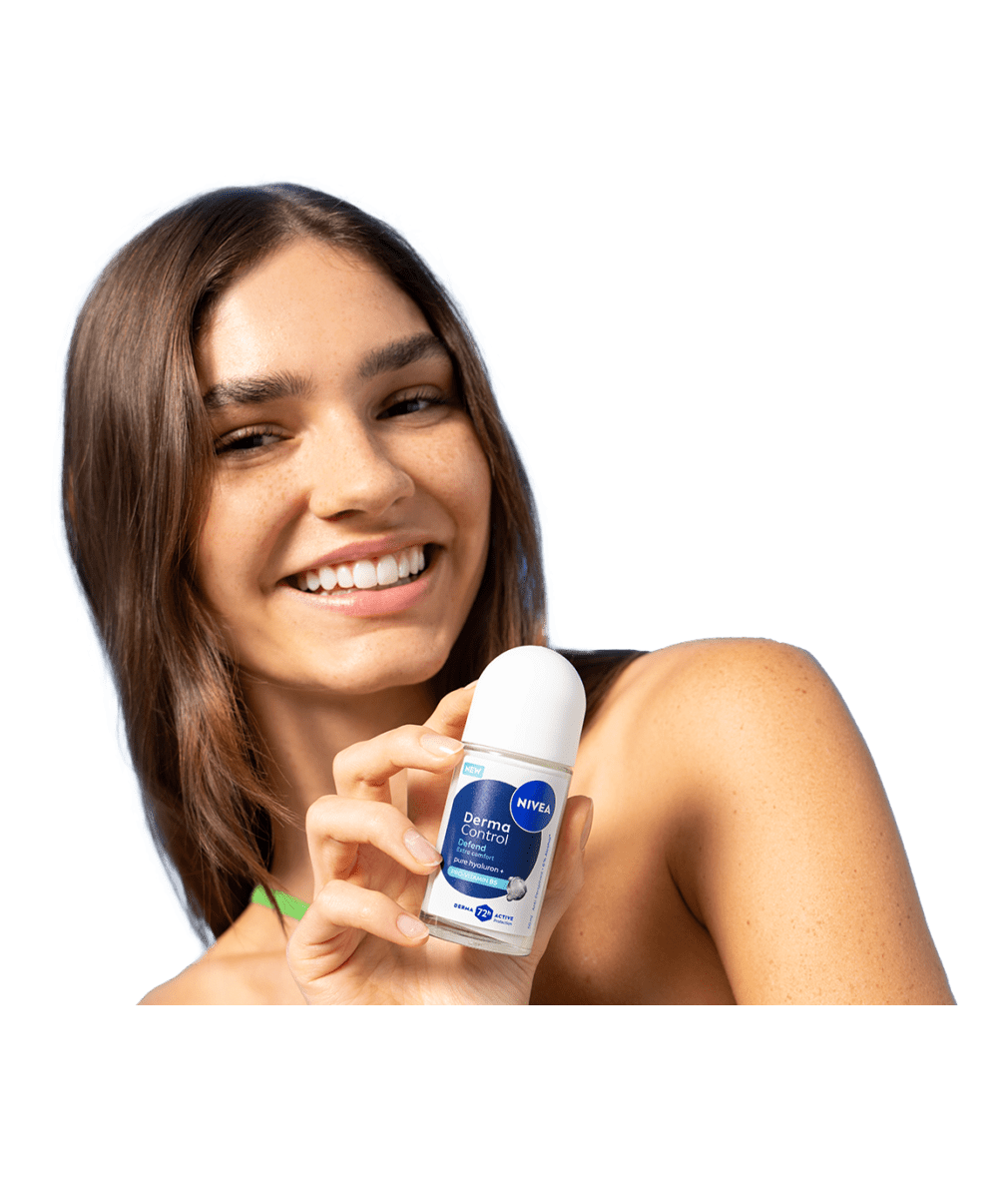 A young smiling woman turns her head while holding up NIVEA Derma Control Defend Deo Roll-On.