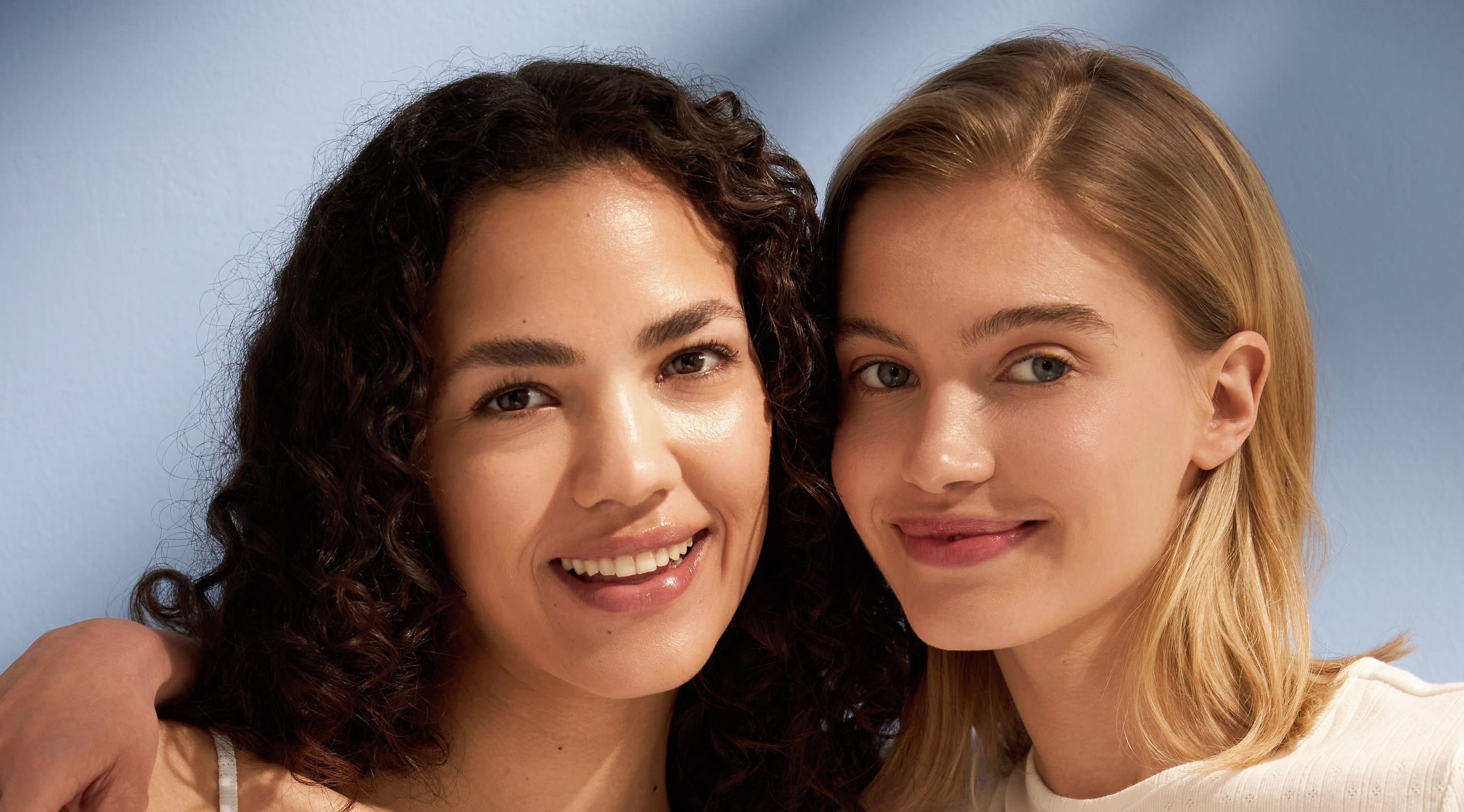 Två personer som står och håller om varandra och tittar in kameran