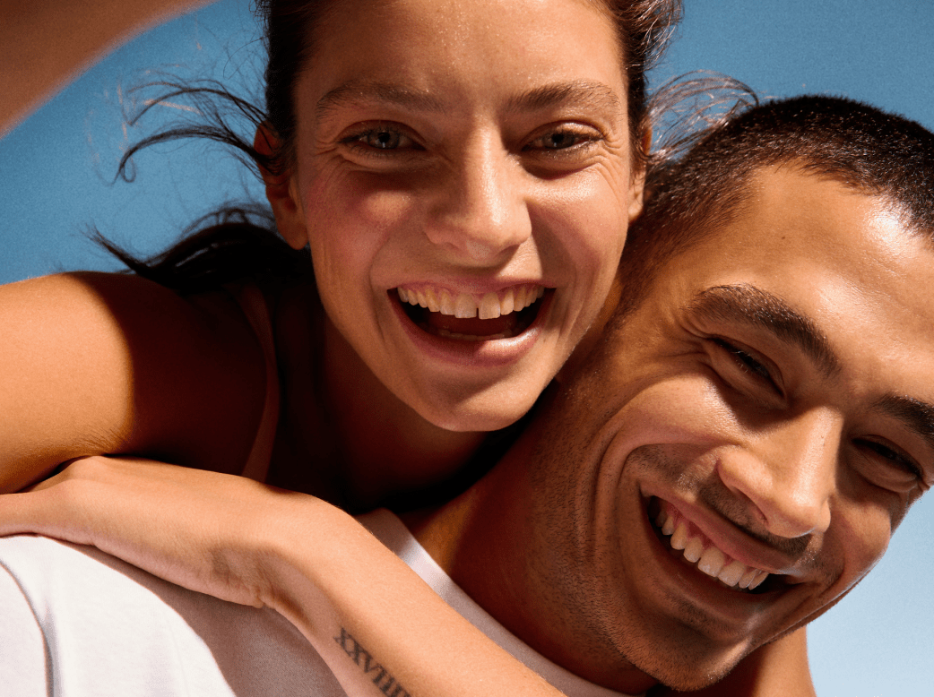 A man and a woman smiling, showcasing clear skin