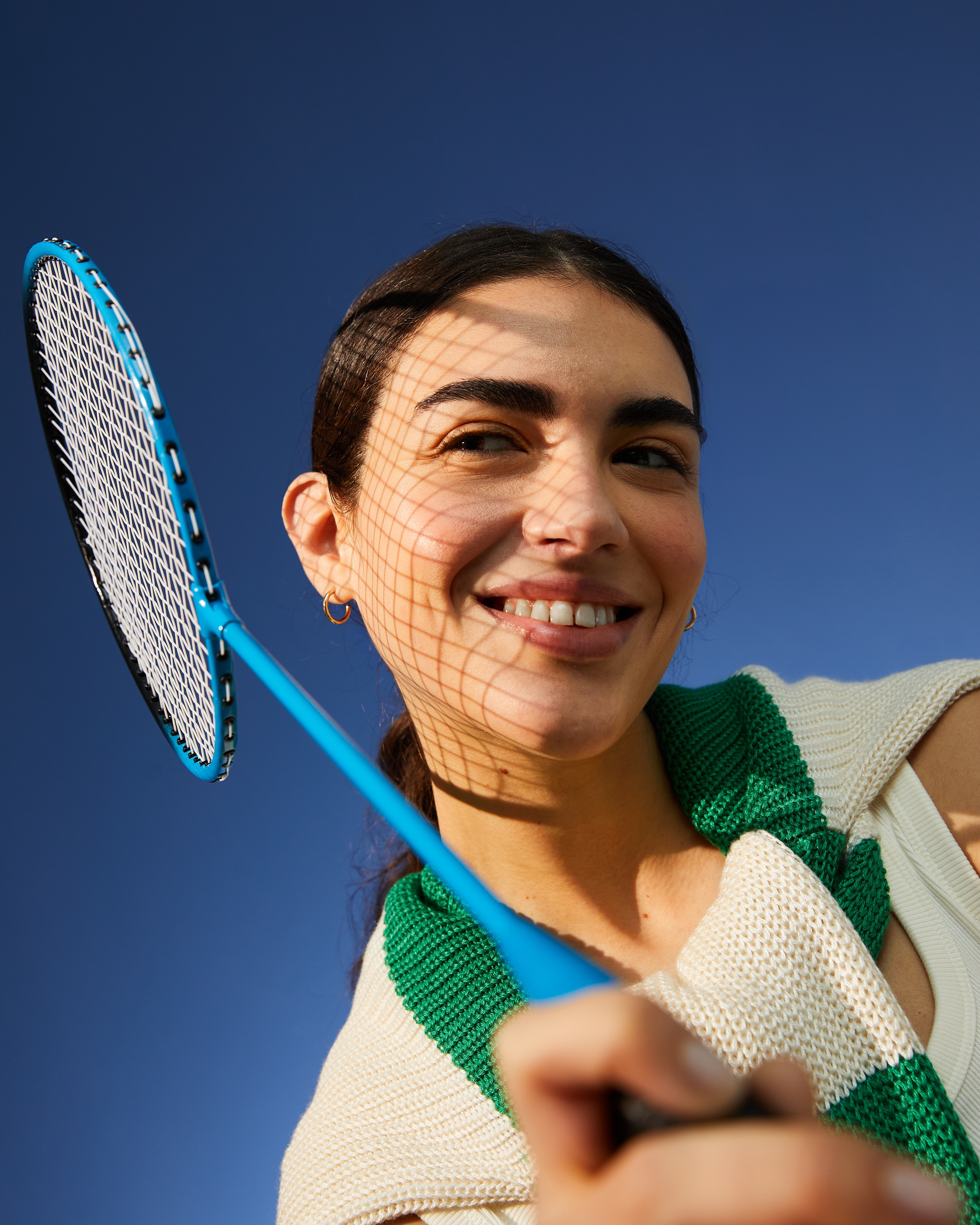 Kvinna ler åt sidan och håller i ett badmintonrack