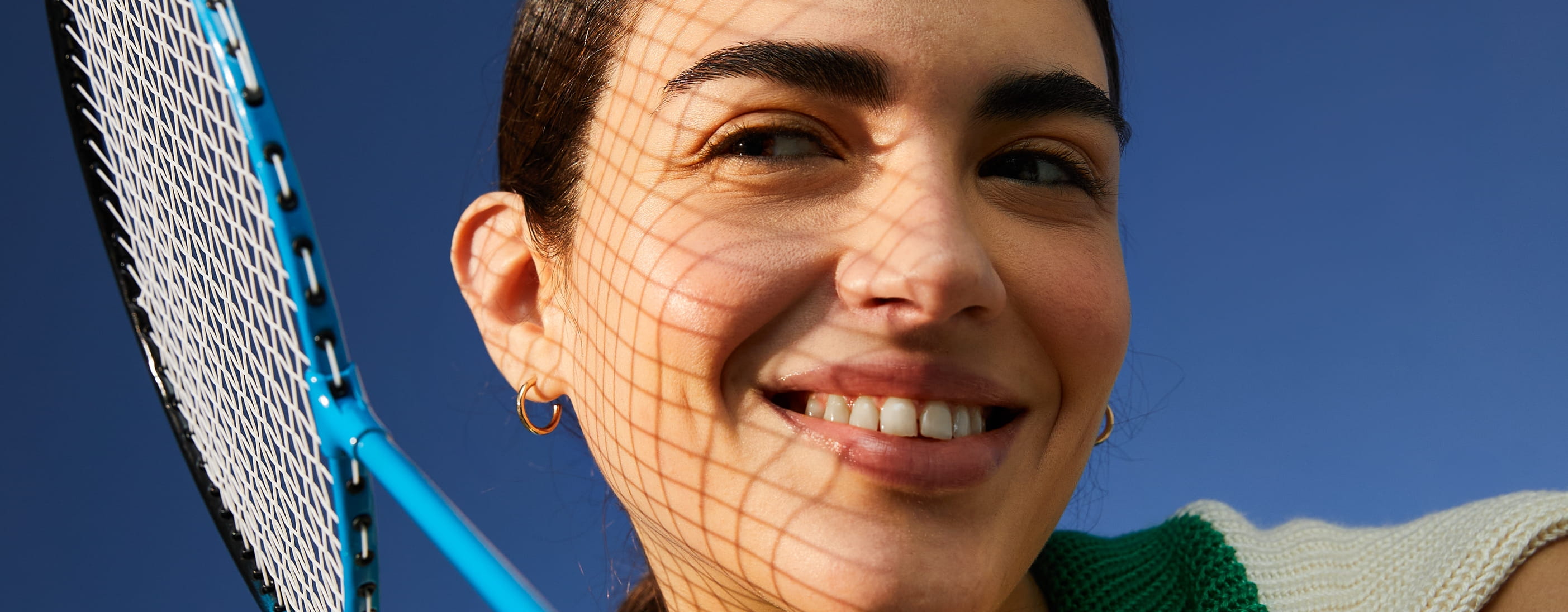 Kvinna ler åt sidan och håller i ett badmintonrack