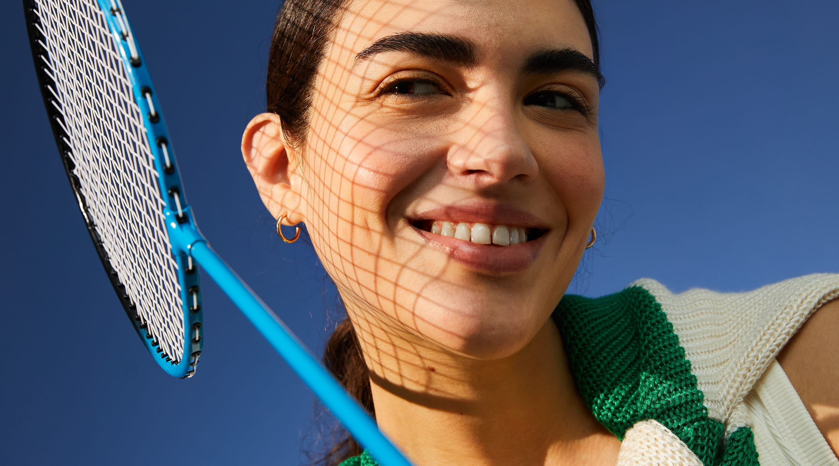 Kvinna ler, kollar åt sidan och håller i ett badmintonrack