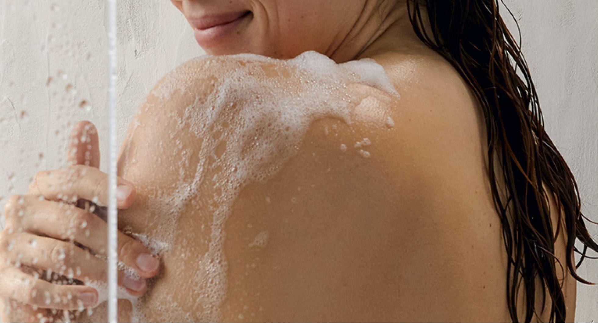 A woman bathing herself with NIVEA in-shower lotion