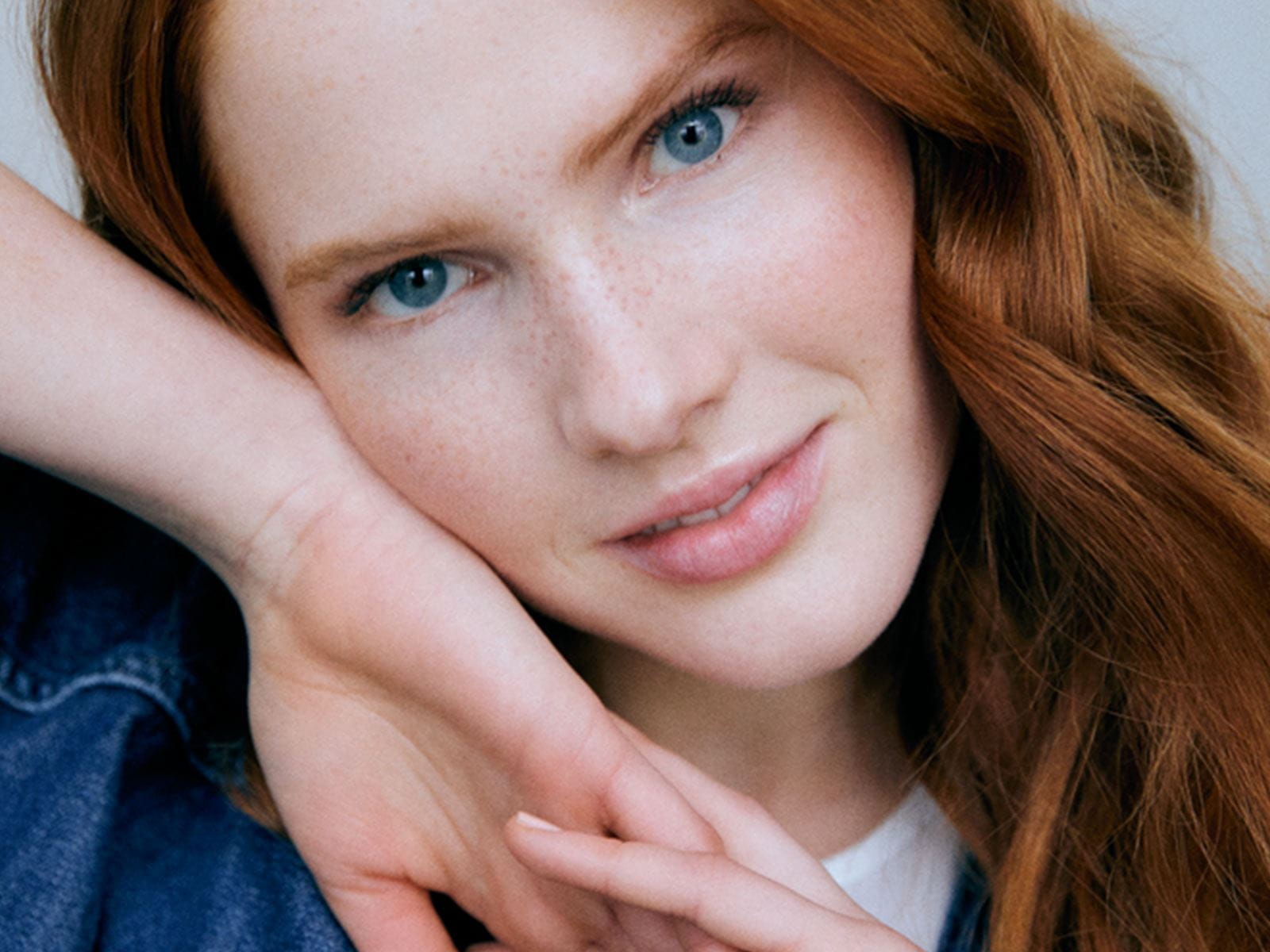 View of a person with red hair smiling while gazing into the camera.