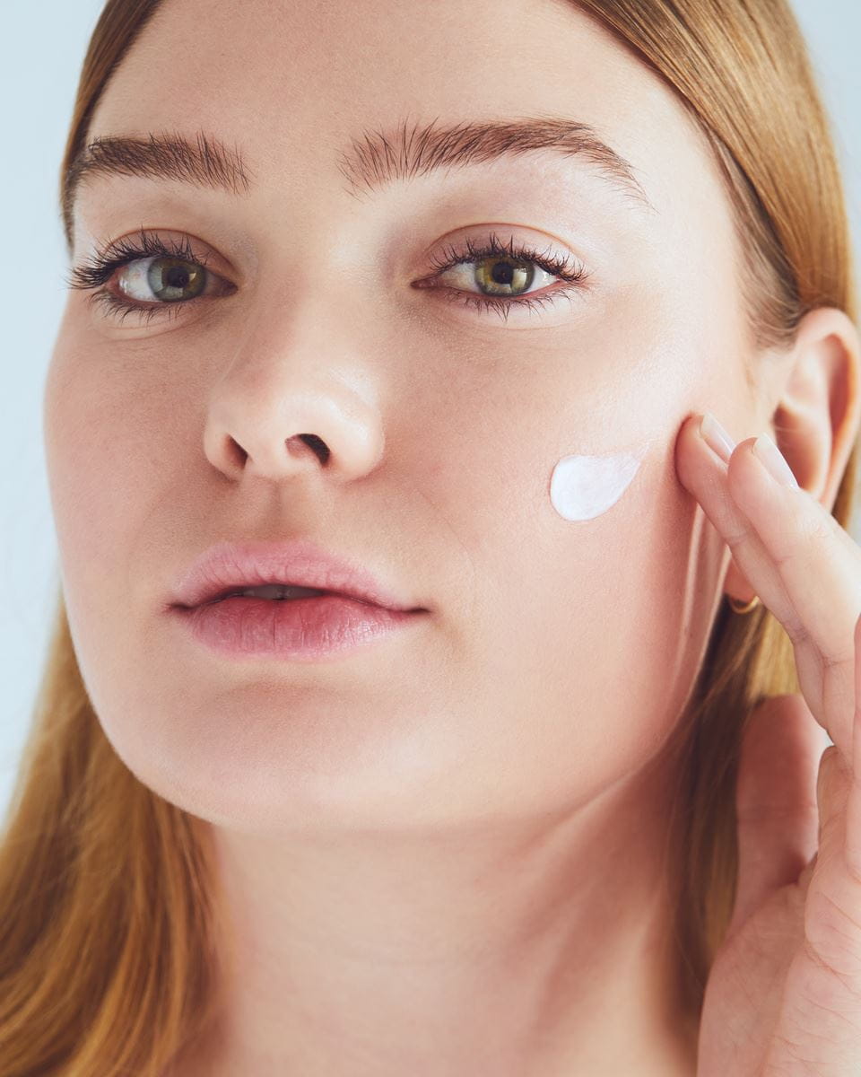 woman applying cream on her face