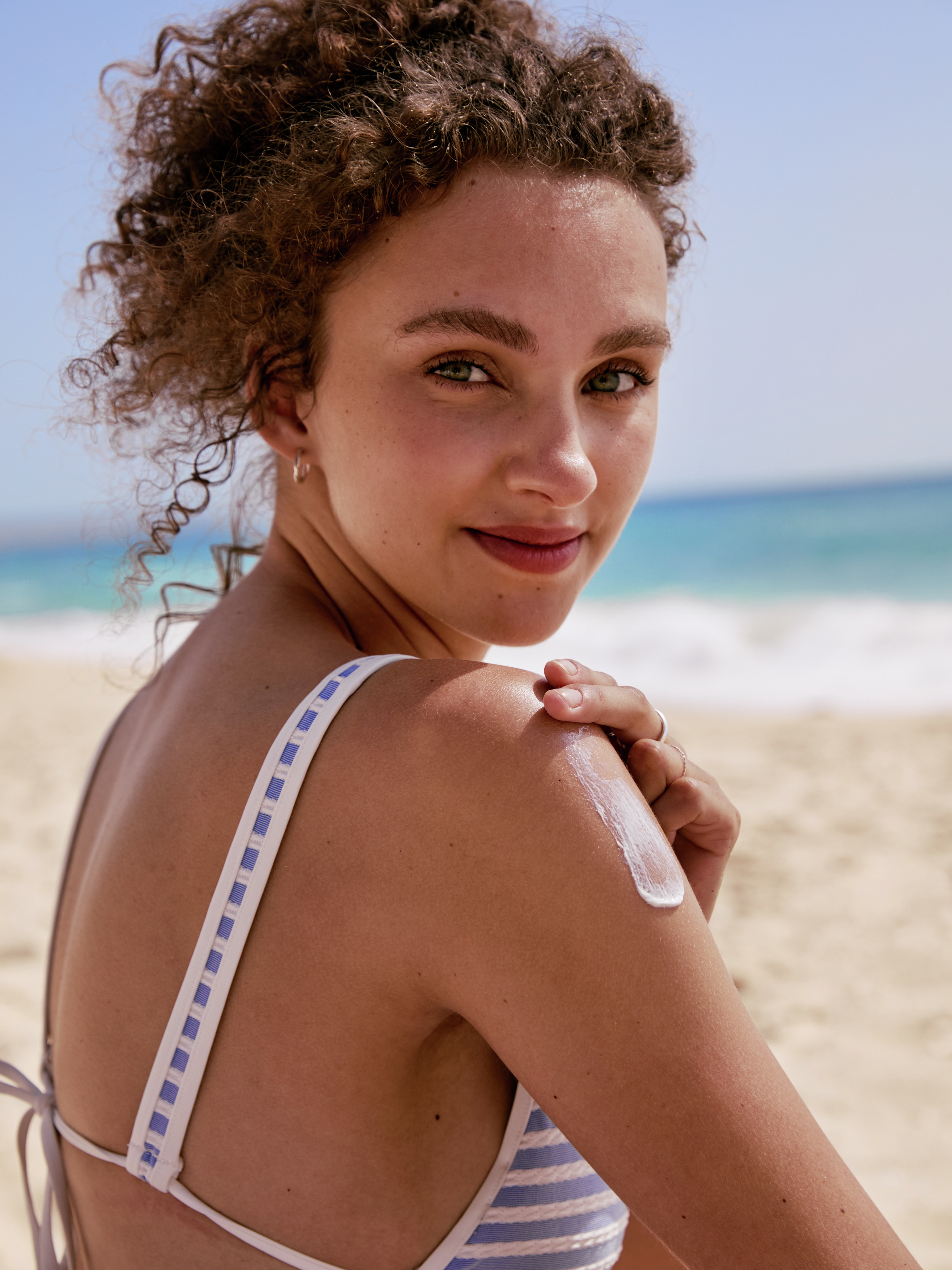woman applying sunscreen at the beach