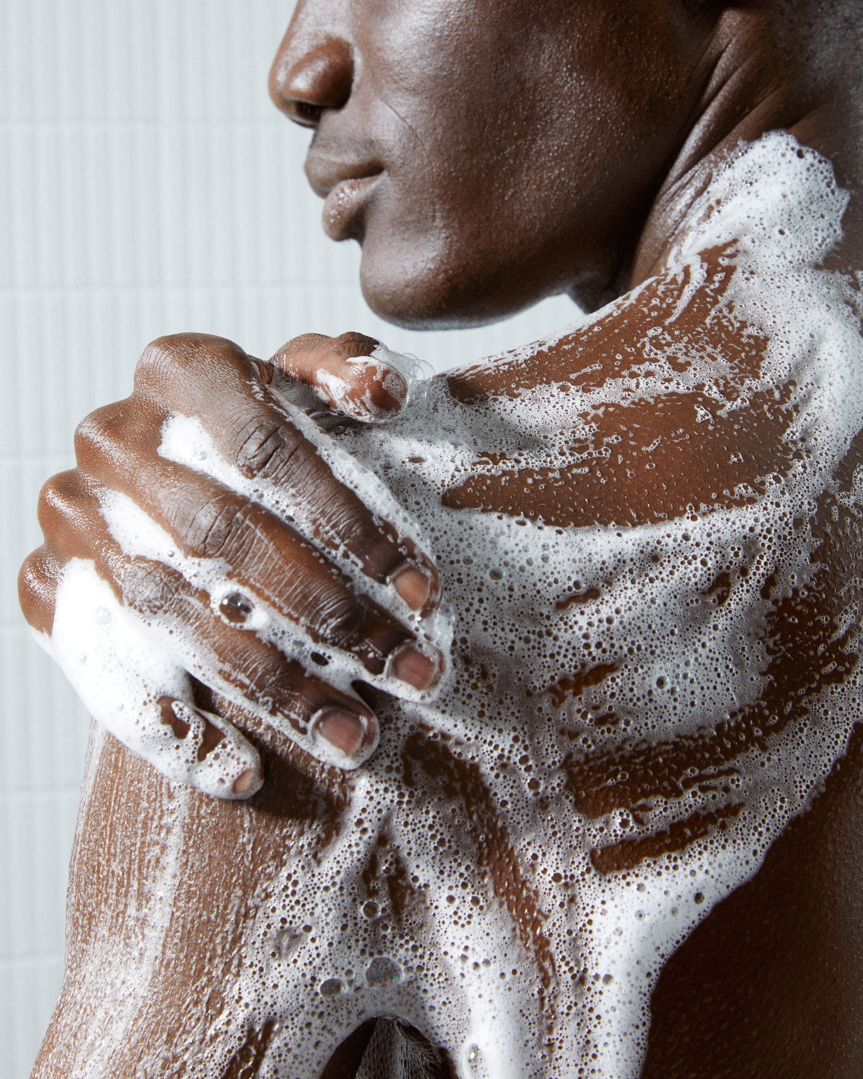 En närbild på en hand på en axel med lödder från en dushtvål