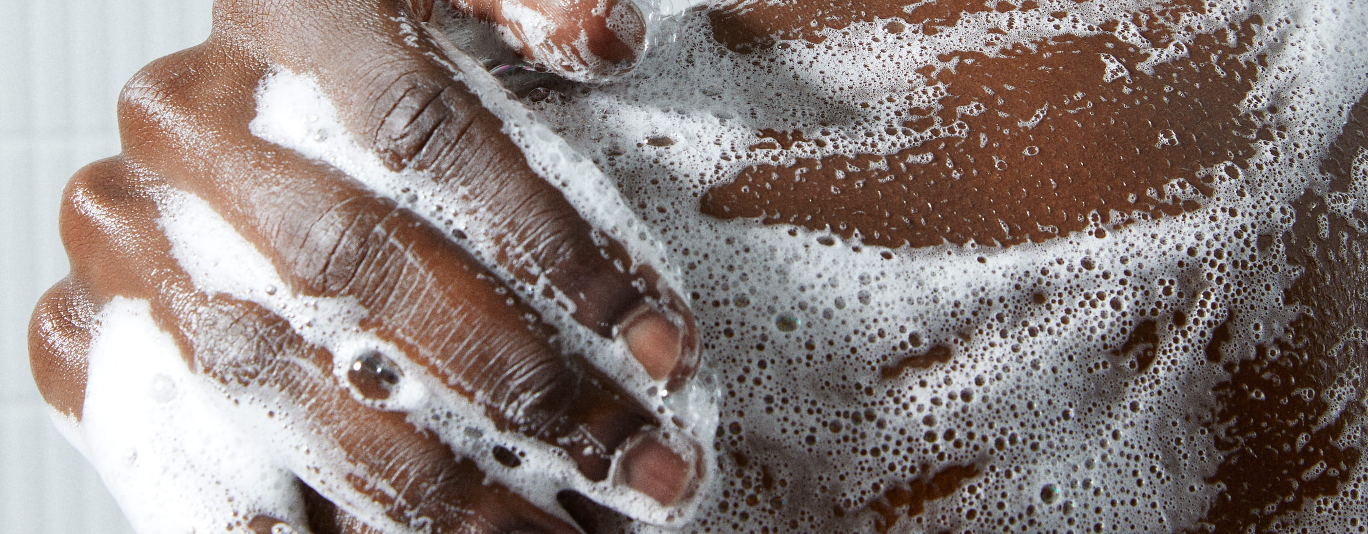 En närbild på en hand på en axel med lödder från en dushtvål