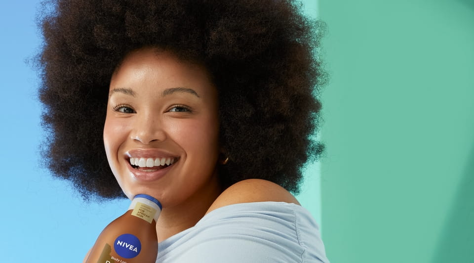 Jovem mulher com cabelo afro a usar a Loção Corporal Radiante e Bonita da Nivea