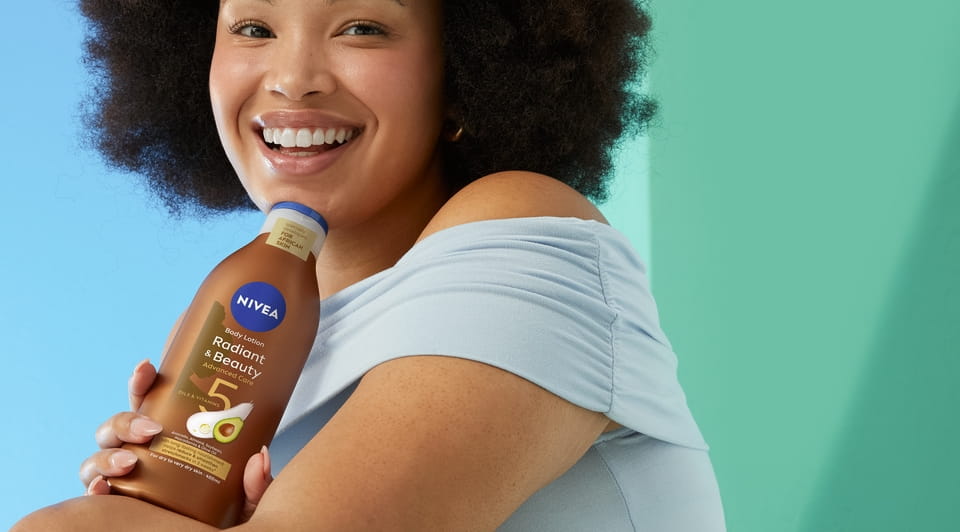Afro hair young woman using Nivea Radiant and Beauty Body Lotion
