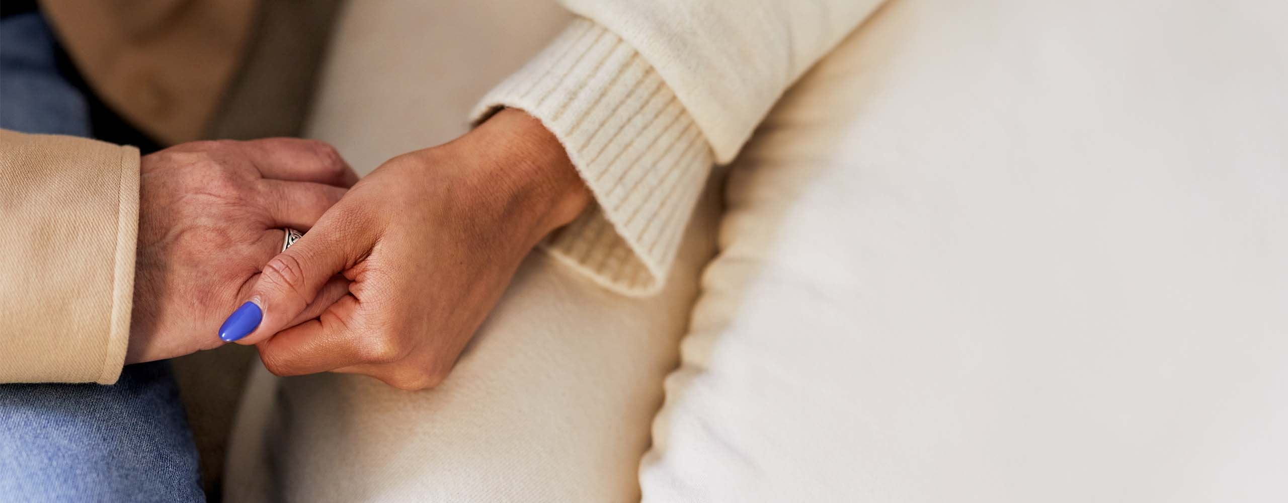 Two people holding each other's hands while delicately places on their lap.