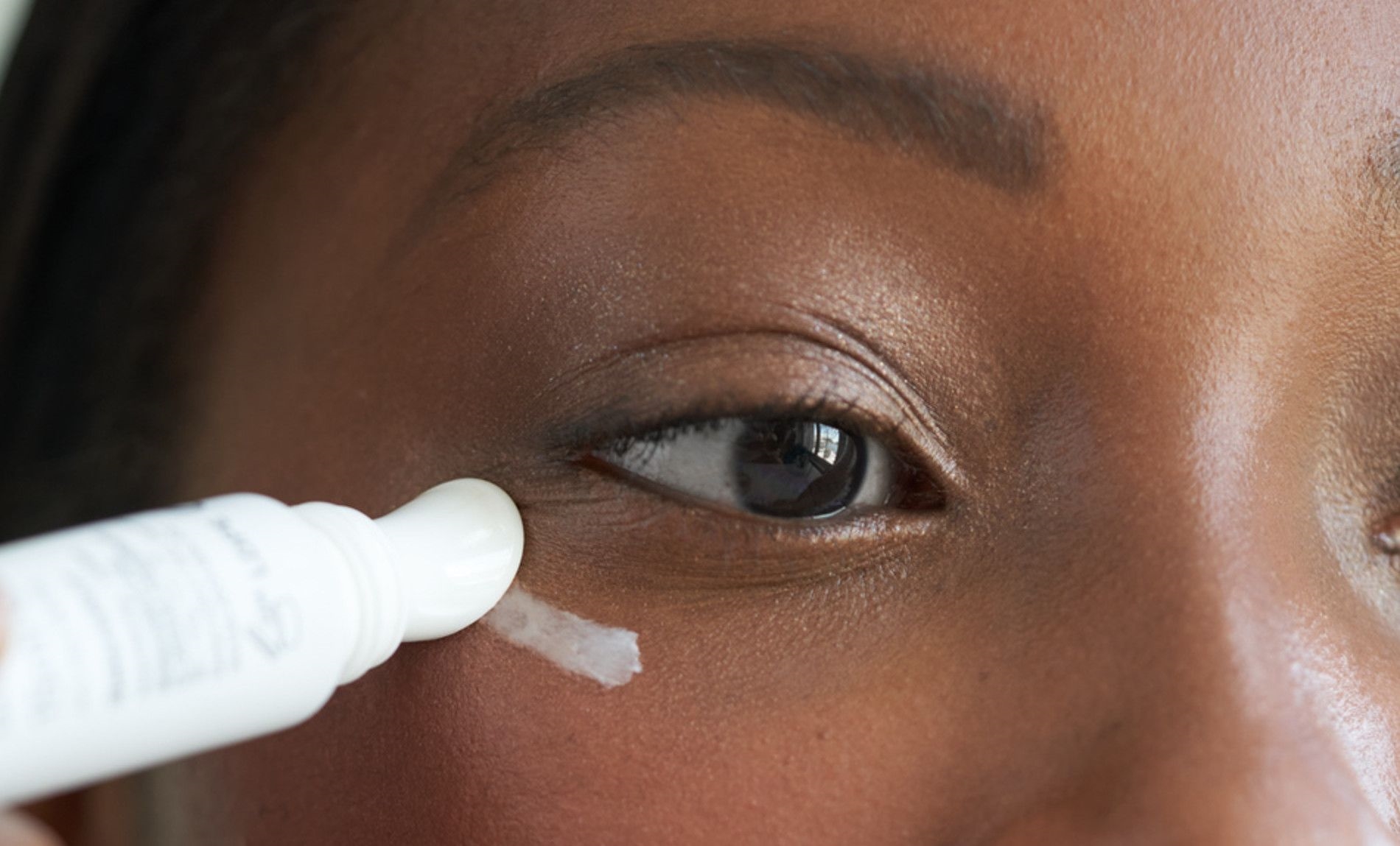 mulher aplicando creme na regiao dos olhos