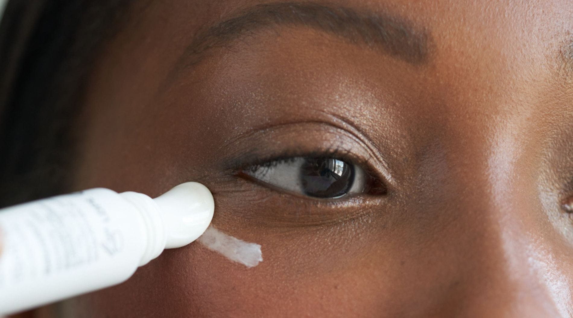 mulher aplicando creme na regiao dos olhos