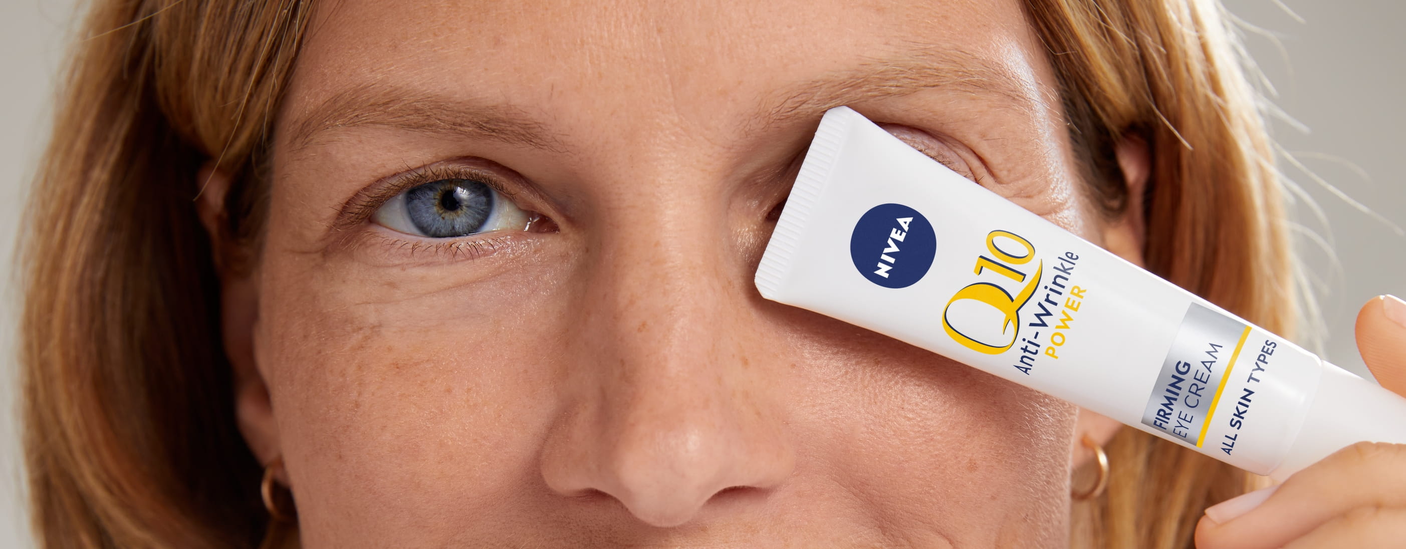 Donna che utilizza NIVEA Q10 Anti-Rughe POWER EXTRA FIRMING EYE CREAM