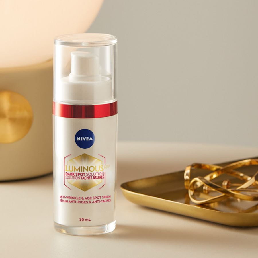 Photo en plan rapproché d'un flacon de 30 ml de LUMINOUS630® SOLUTION TACHES BRUNES SÉRUM ANTI-RIDES & ANTI-TACHES de NIVEA sur une table.