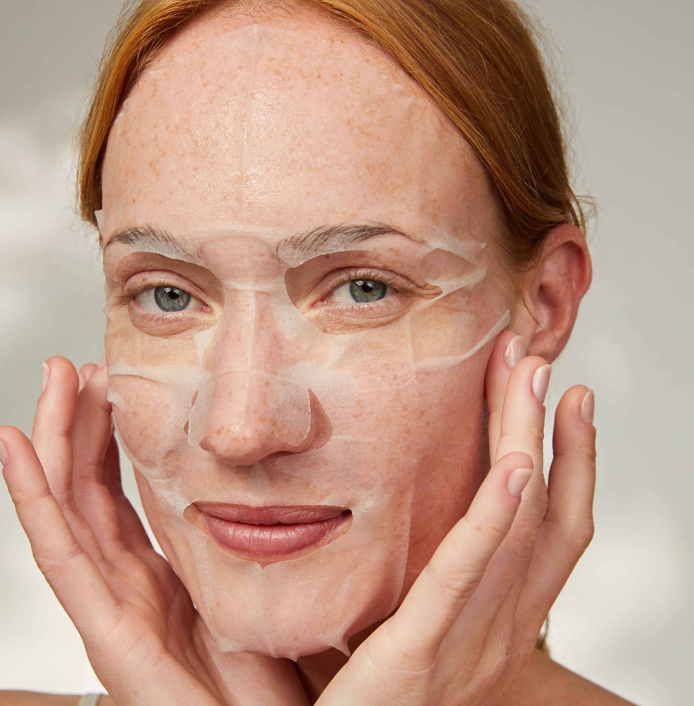 Person applicerar ansiktsmask och ler in i kameran