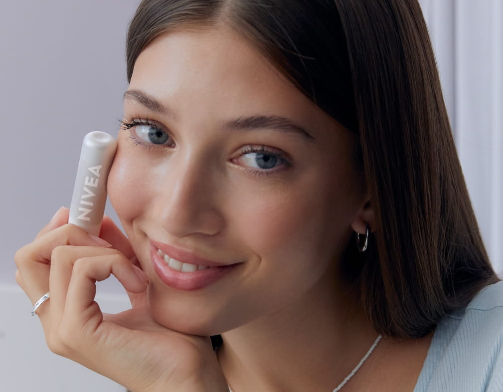 Jonge vrouw die NIVEA Hyaluron Moisture Plus Lip Balm gebruikt