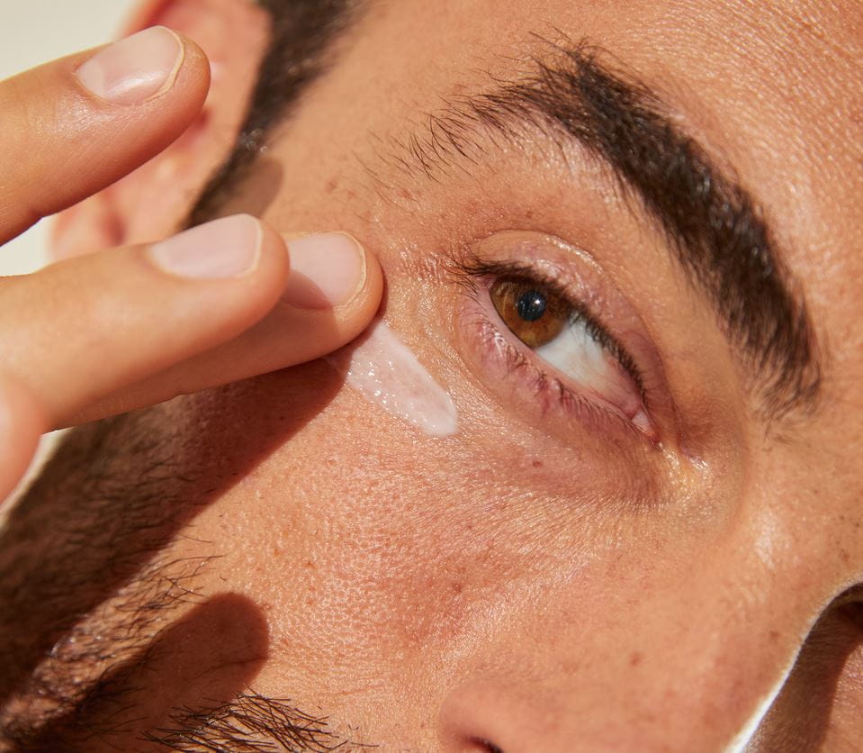 Junger Mann trägt Nivea-Augencreme auf