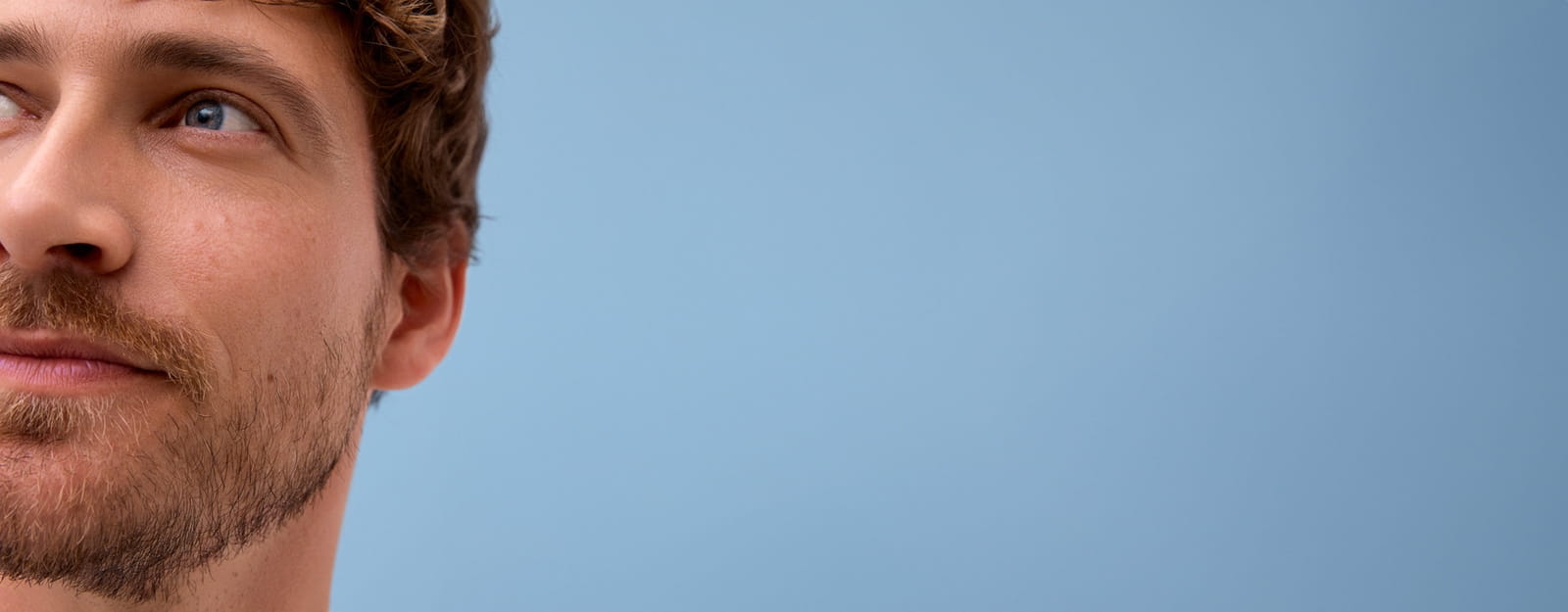 Gros plan d'une personne regardant au loin, sur un fond bleu.