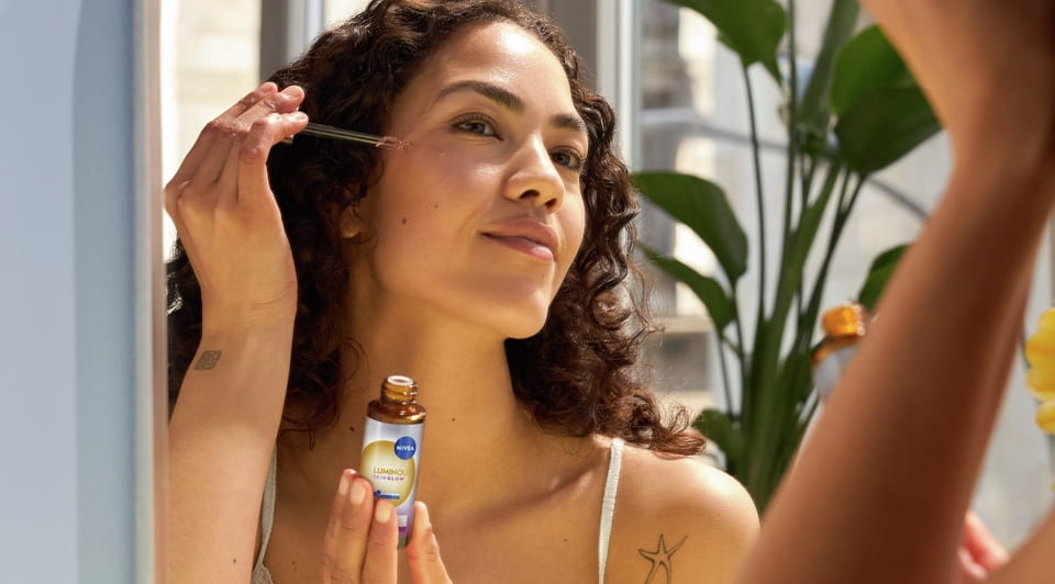 Mlada žena nanosi Nivea serum za lice