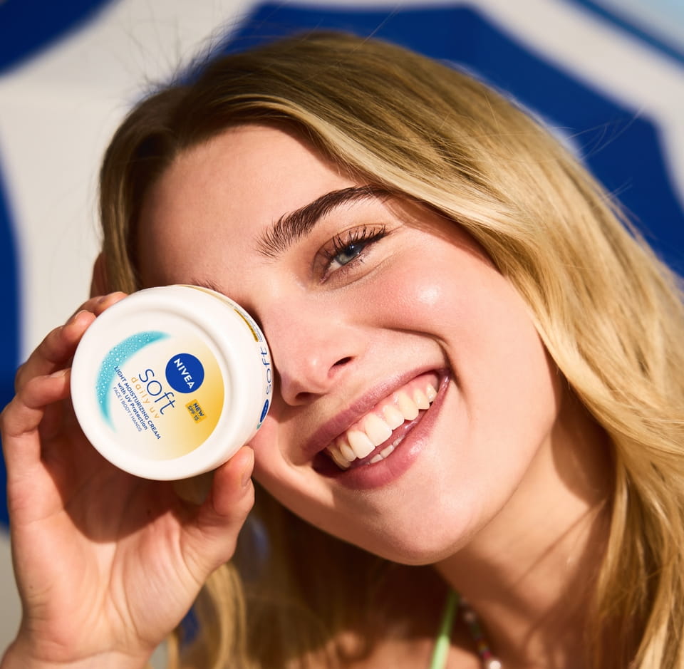 Jonge vrouw die Nivea Soft crème gebruikt
