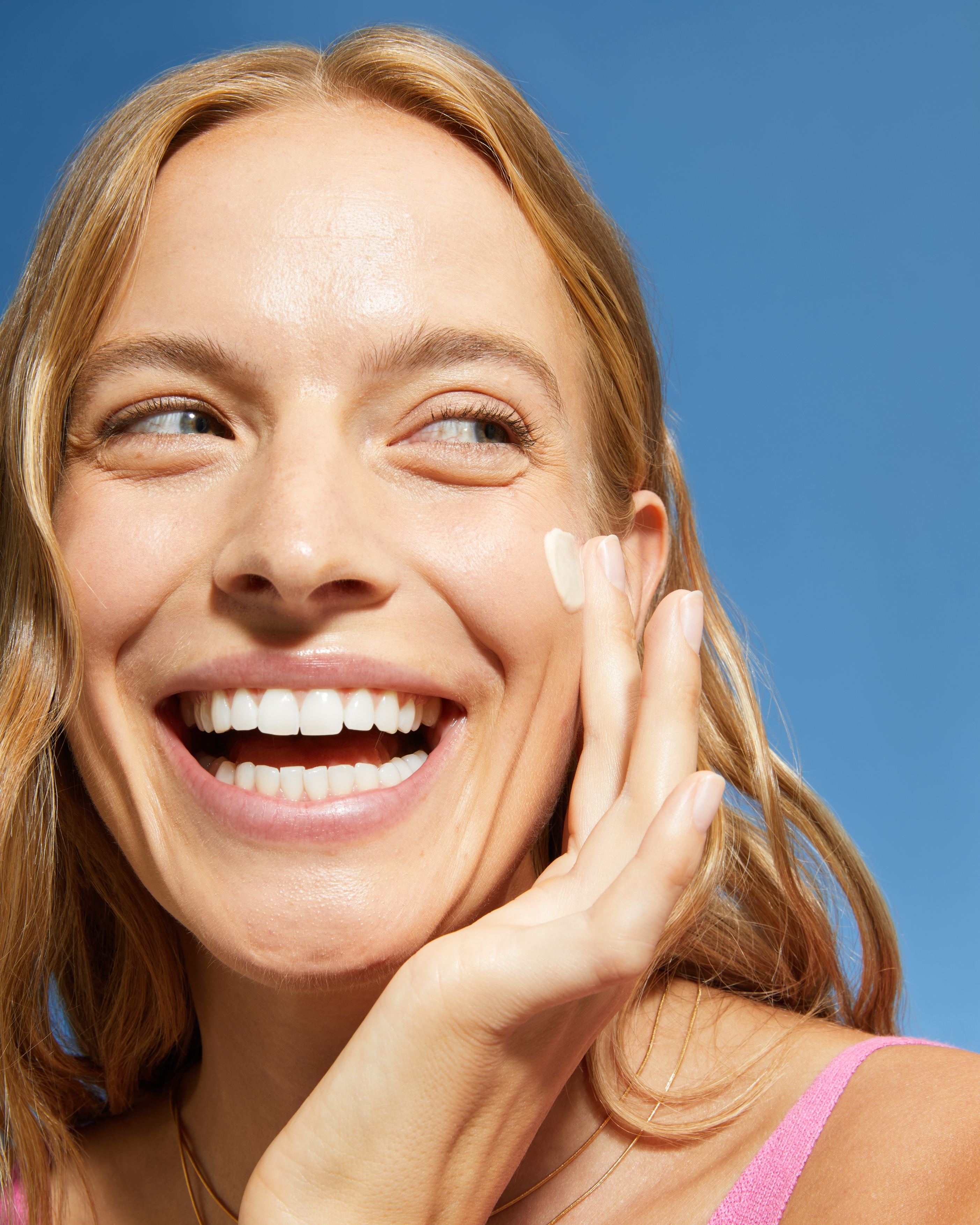 glad kvinna som applicerar kräm på kinden