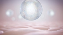 Eine transparente, perlenartige Kugel mit blauen Partikeln im Inneren liegt auf einer glatten, welligen, hautähnlichen Oberfläche.
