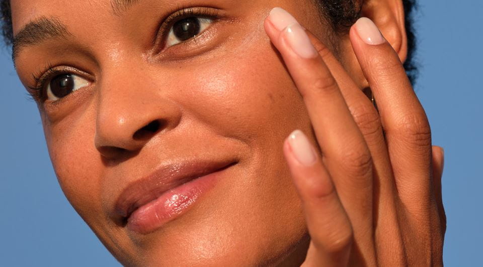 Vrouw met stralende huid raakt gezicht aan