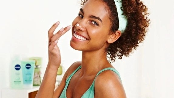 jovem negra passando hidratante no nariz