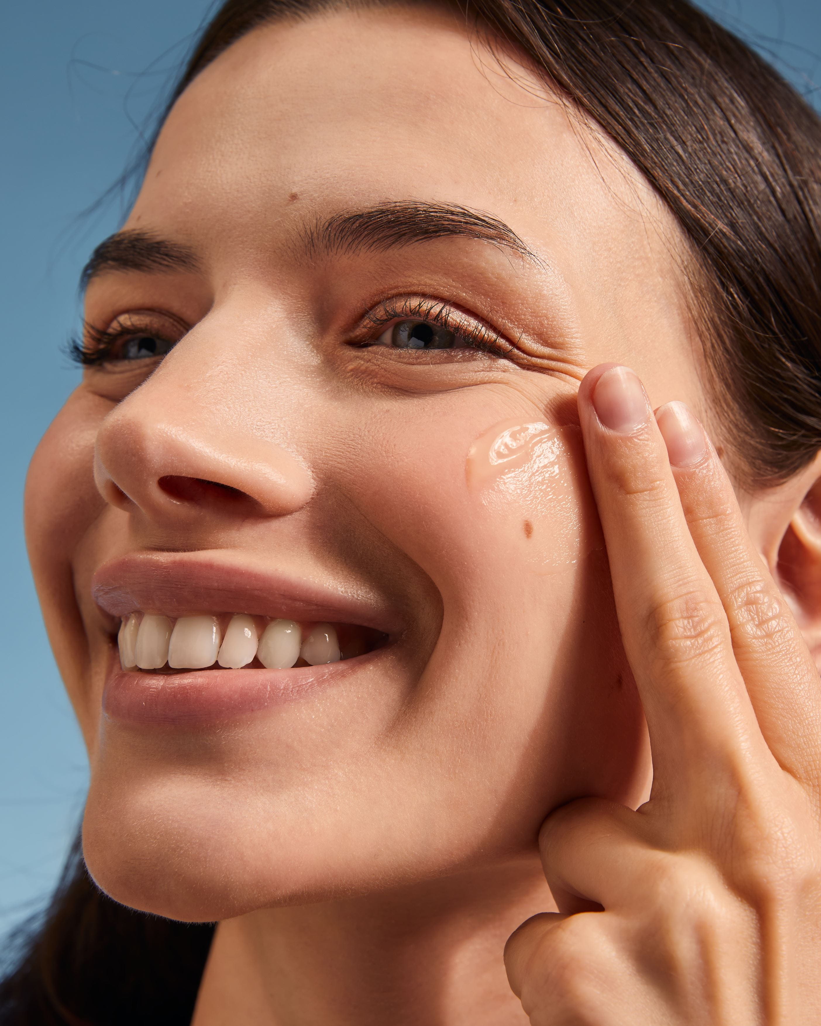 woman smiling while applying sunscreen