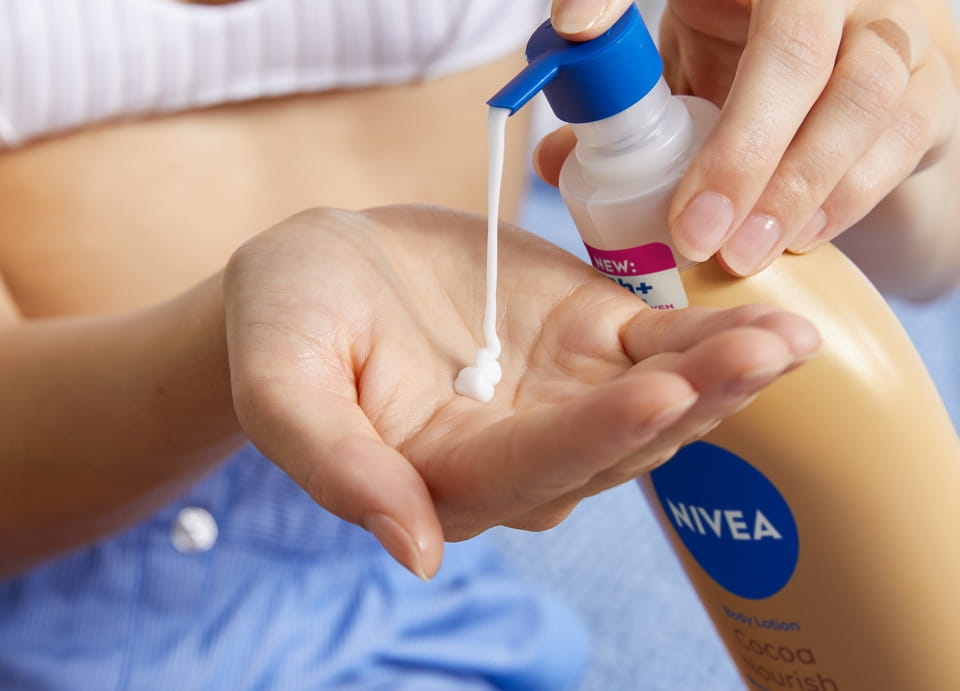 Woman applying Nivea body lotion