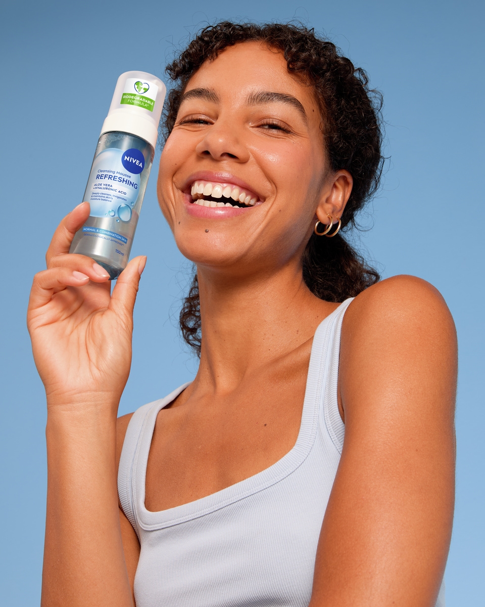 Giovane donna che utilizza la mousse detergente Nivea