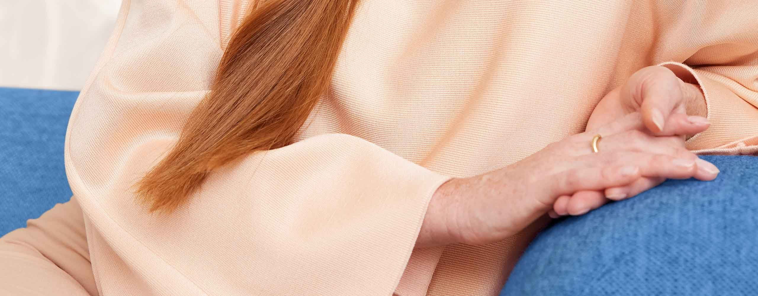 Une personne portant un haut de couleur pêche, assise sur une chaise de couleur bleue.
