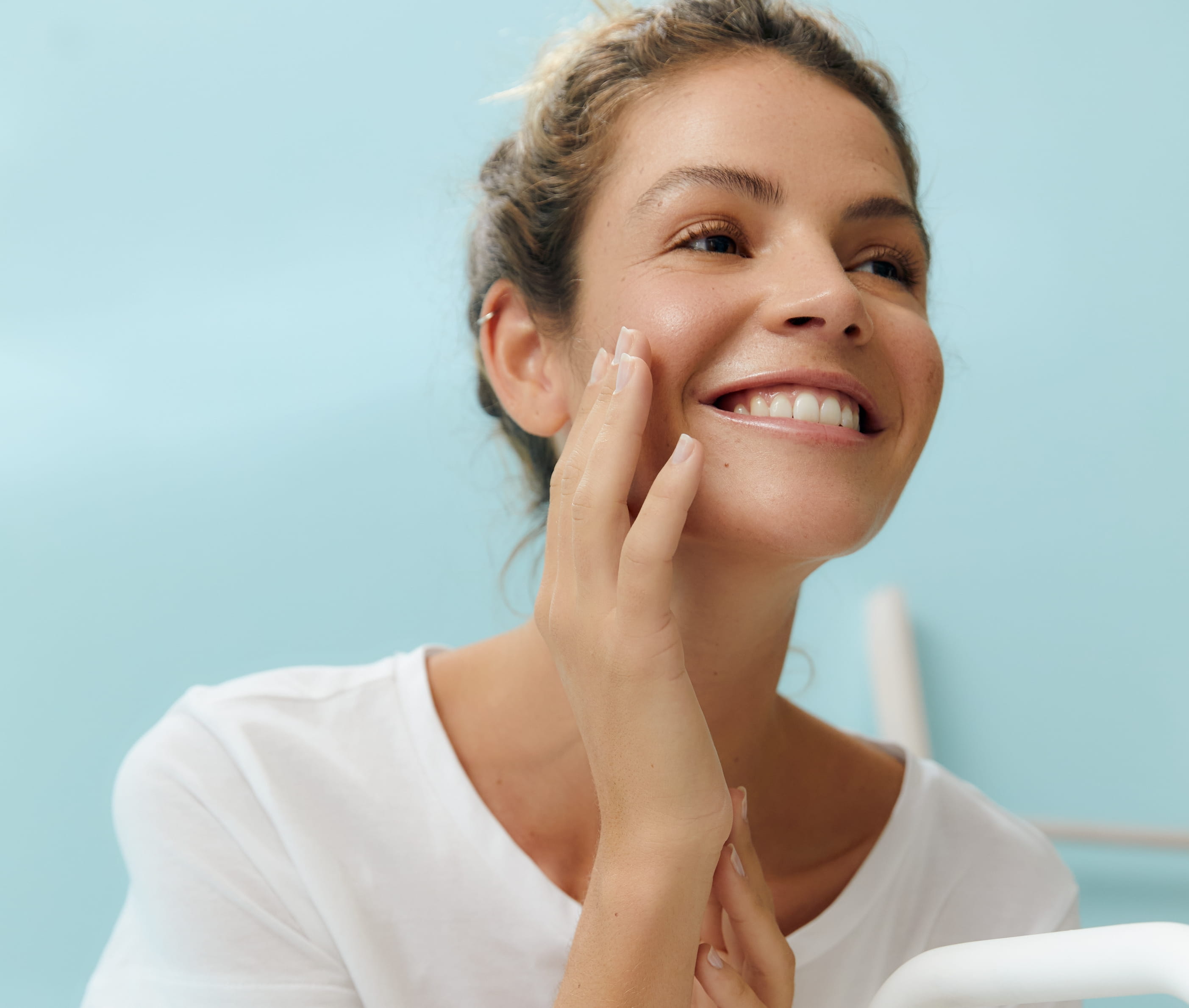 person rör med ena handen på sin kind och ler