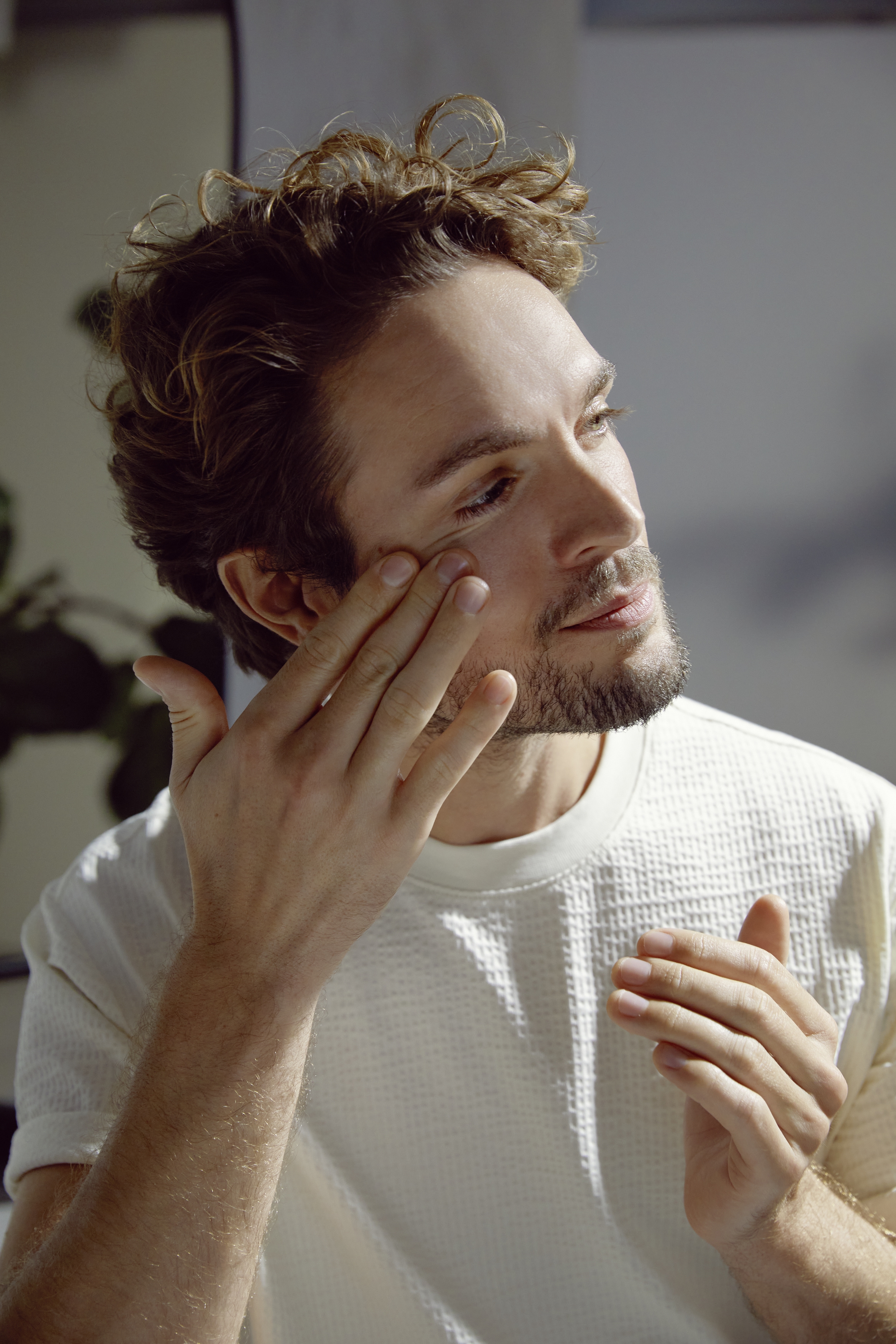 man vidrör sitt ansikte med ena handen, tiltar huvudet åt sidan