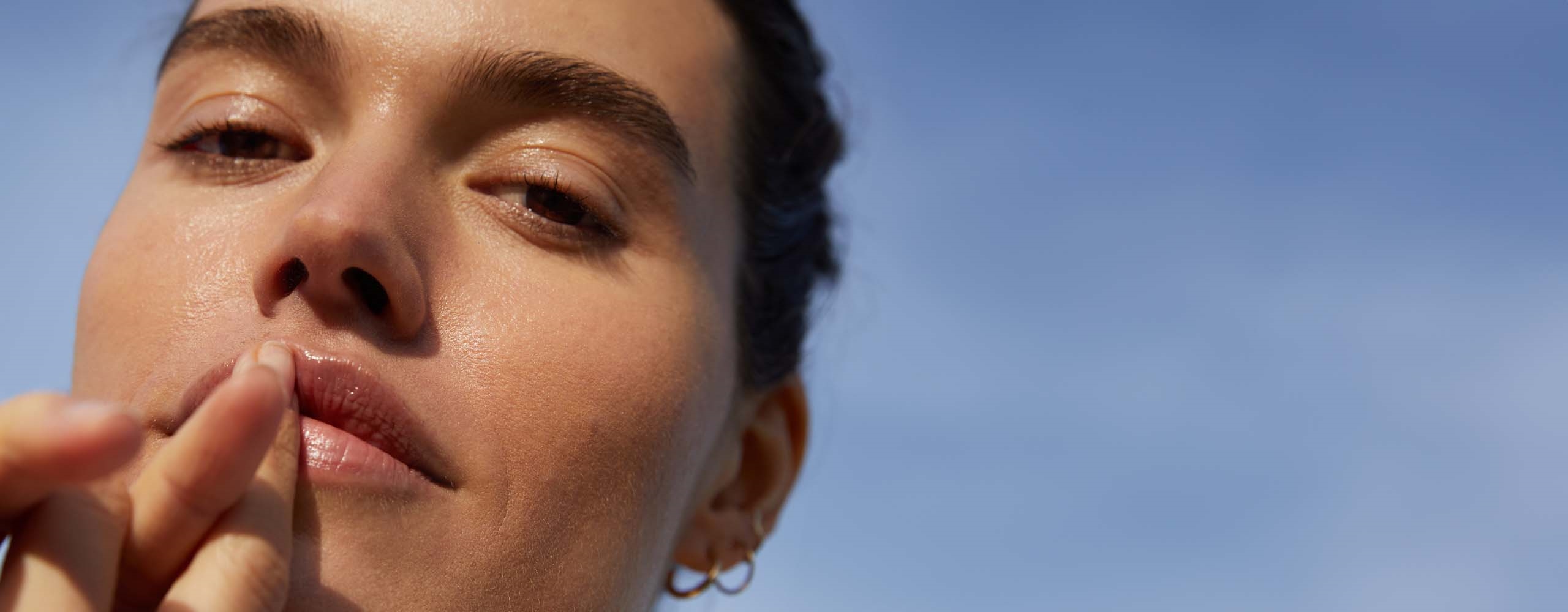View of a person gazing into the camera while holding their fingers to their lips.