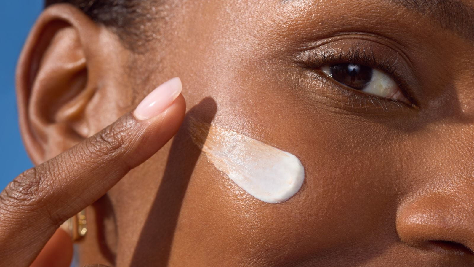 Woman applying NIVEA LUMINOUS630® 3-in-1 CC Fluid on her face to cover, reduce and protect her from new dark spots
