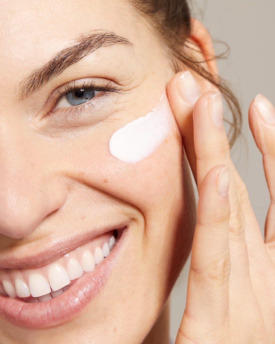 Jeune femme appliquant la crème pour le visage Nivea