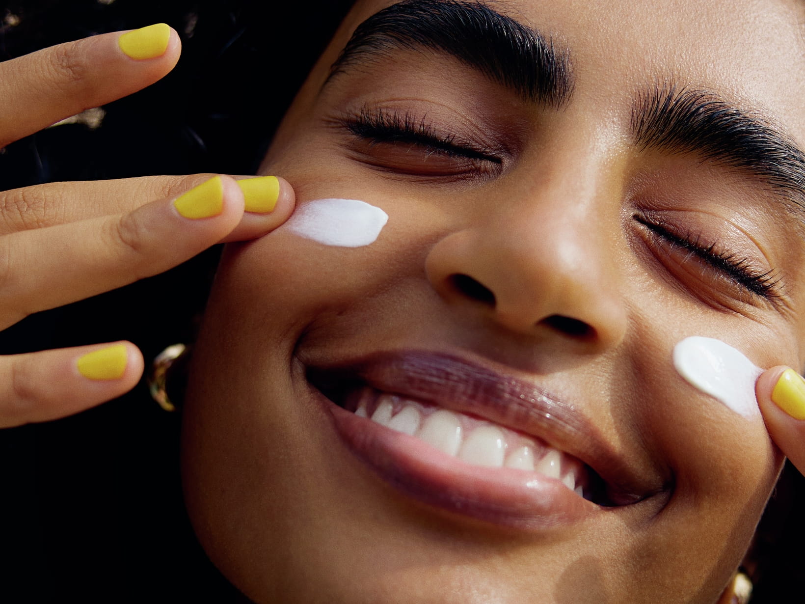 En person som applicerar kräm på kinderna