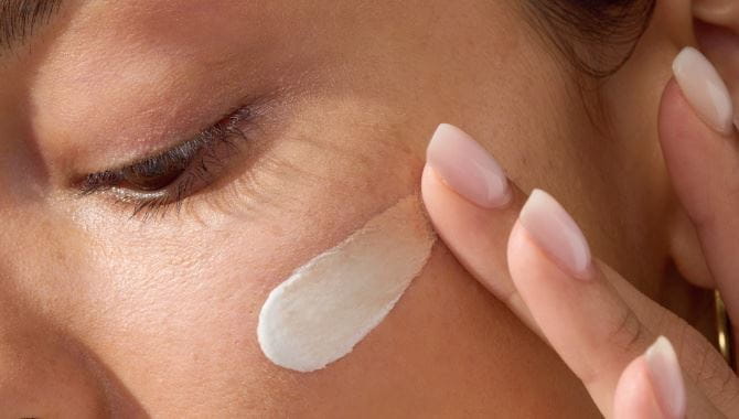 Woman applying NIVEA LUMINOUS630® 3-in-1 CC Fluid on her face as a second step of using this new product