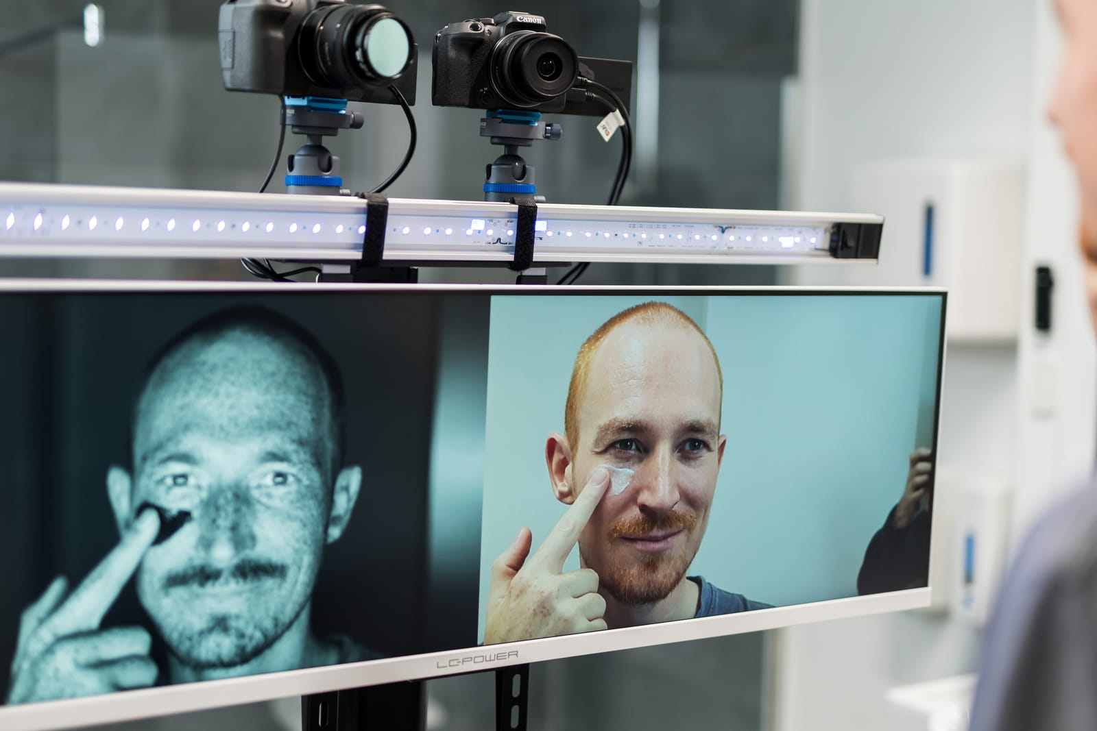 Man applies cream, monitored by cameras and a monitor.
