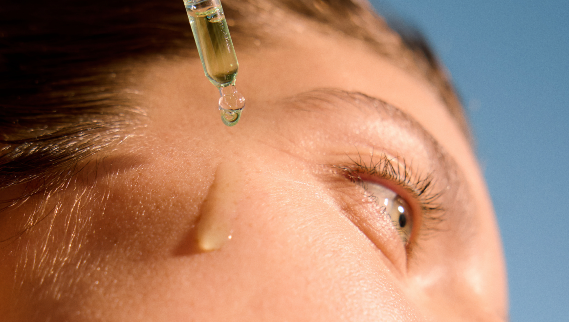  Woman with bright clear skin using vitamin C face serum