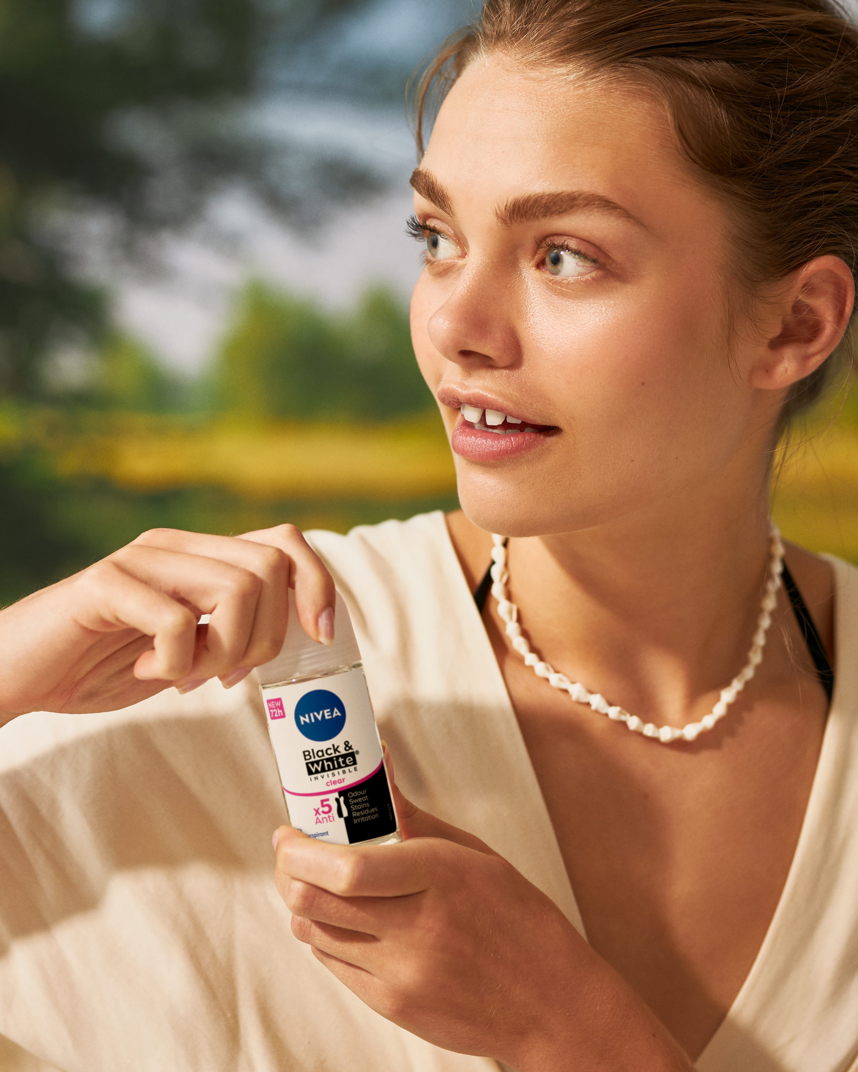 En person som tittar åt vänster och håller en deodorant i handen