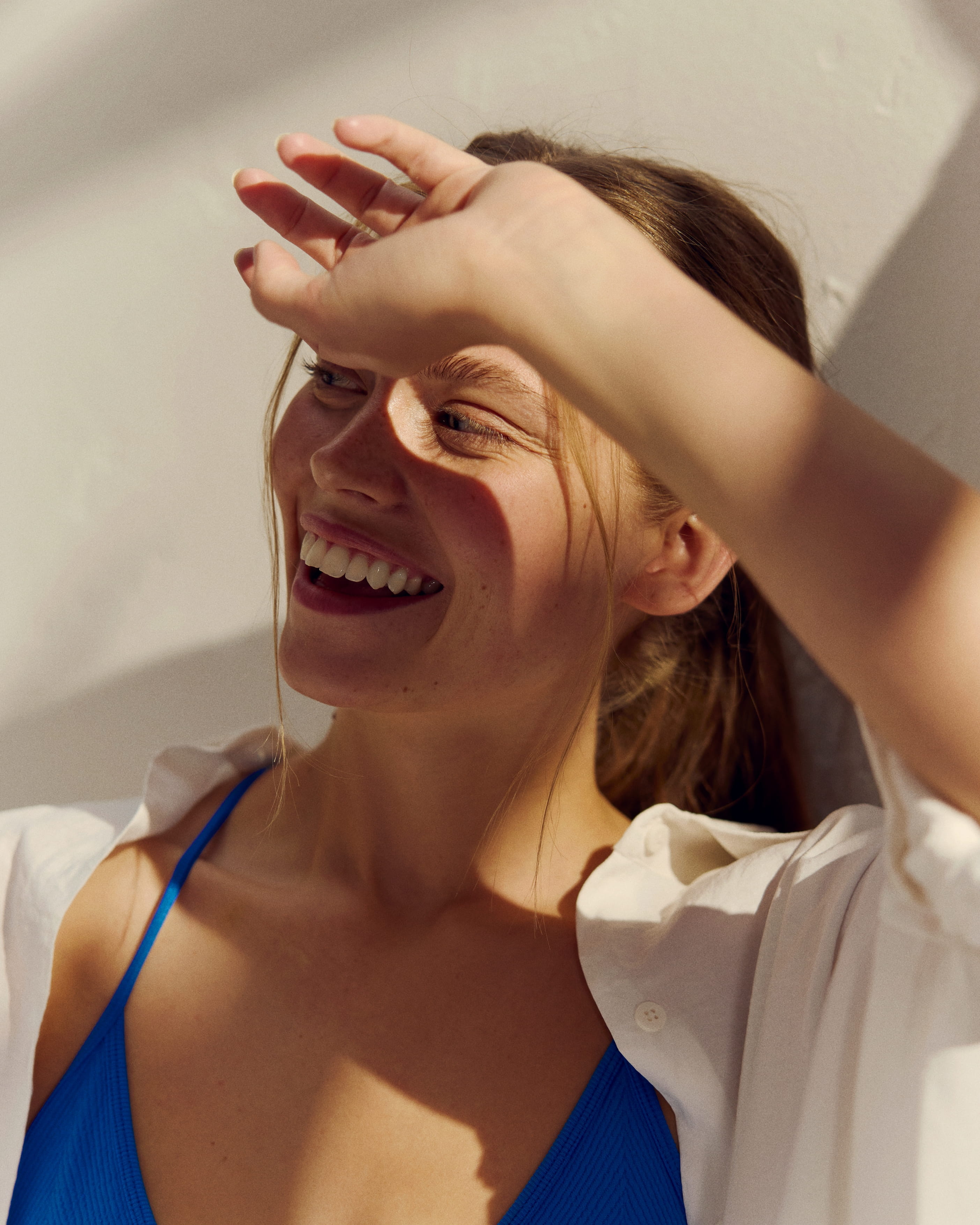 kvinna som står i solen och håller upp en hand för att få skugga